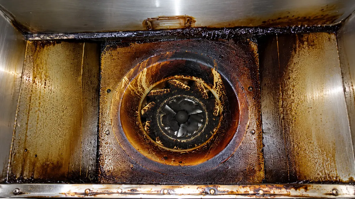 Kitchen hood exhaust fan before cleaning, caked in thick built-up grease