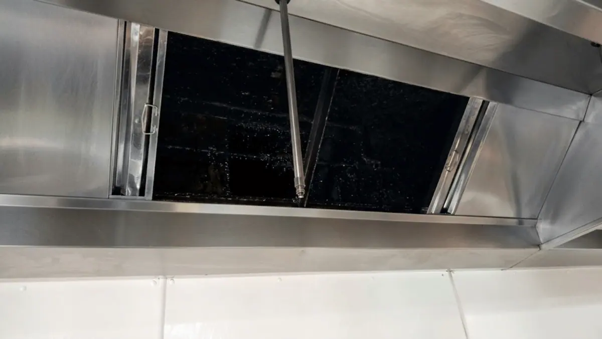 Commercial kitchen hood interior before steam cleaning, coated in built-up grease